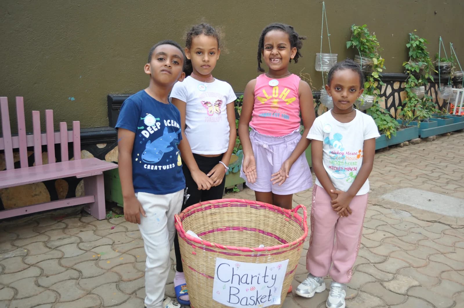 Eco-Bloom children standing beside a basket labelled Charity Basket