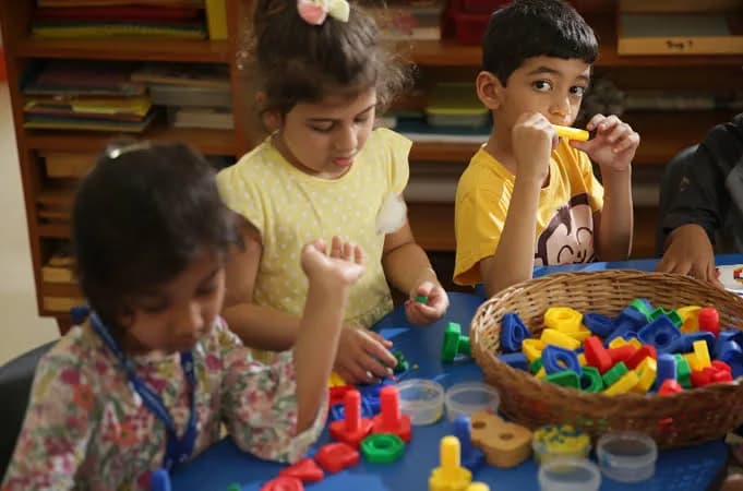 A child working alone at a low table with a wooden material
