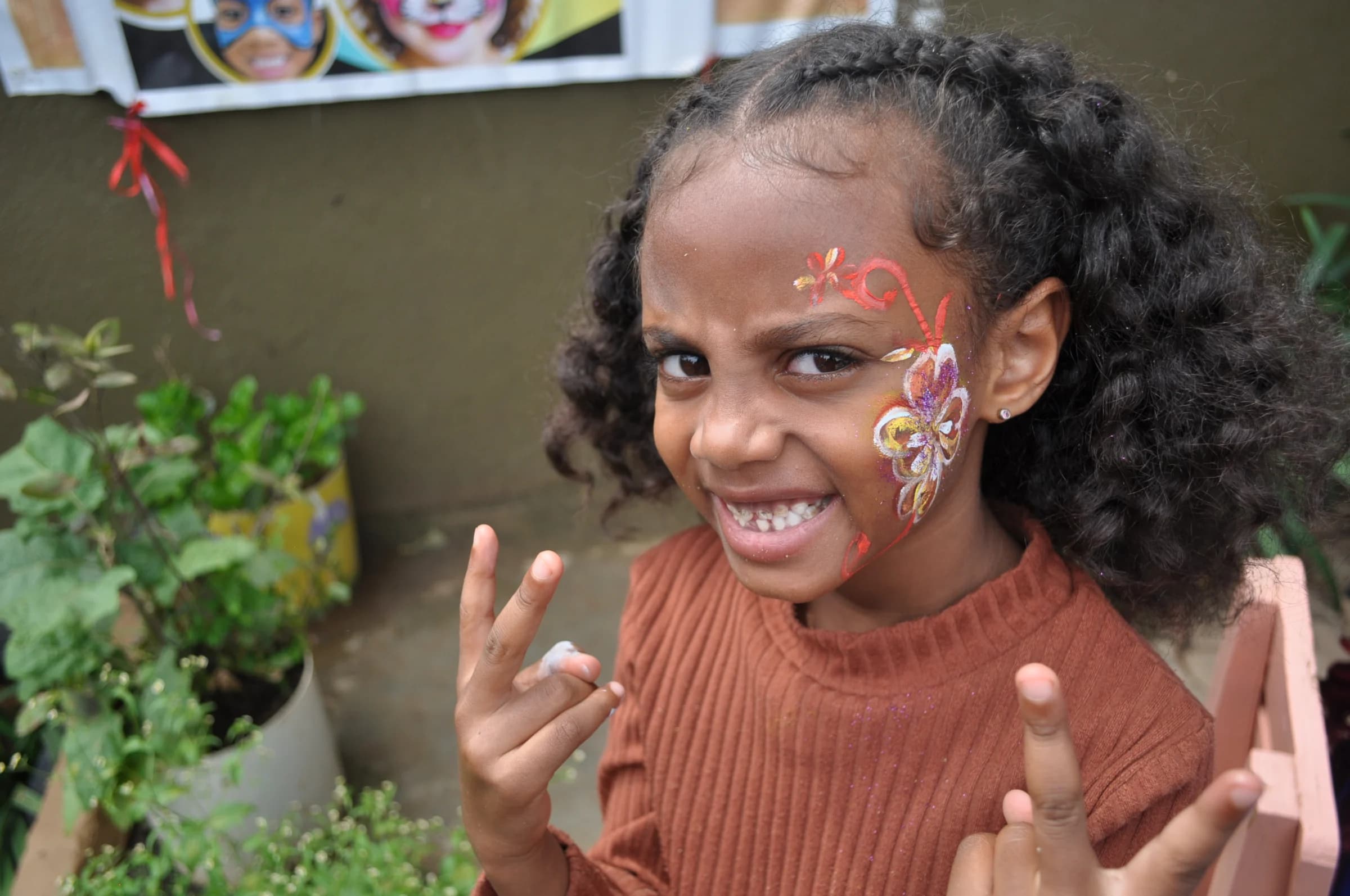 An Eco-Bloom pupil smiling with painted flowers on her face