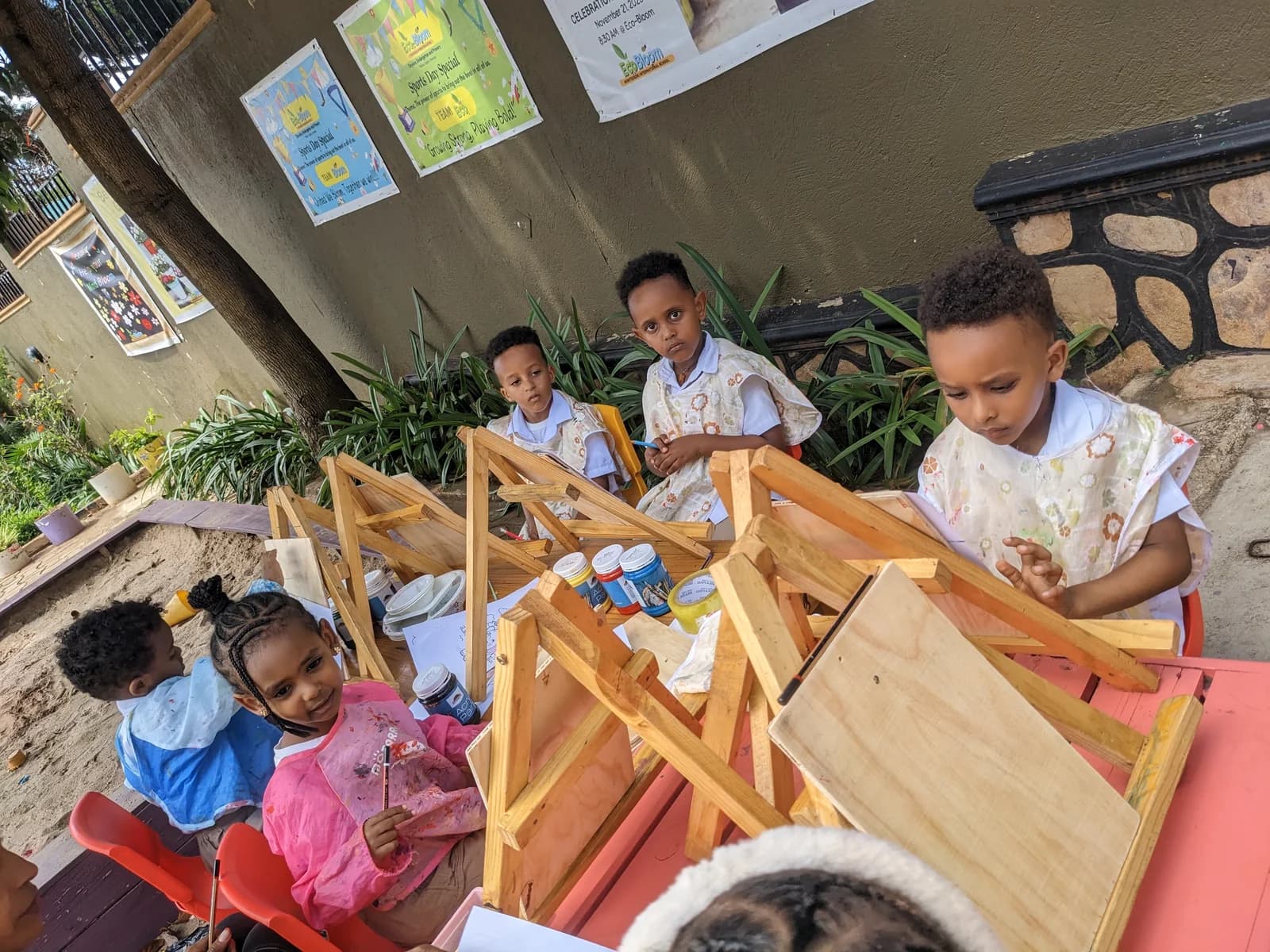 Eco-Bloom children painting at wooden easels