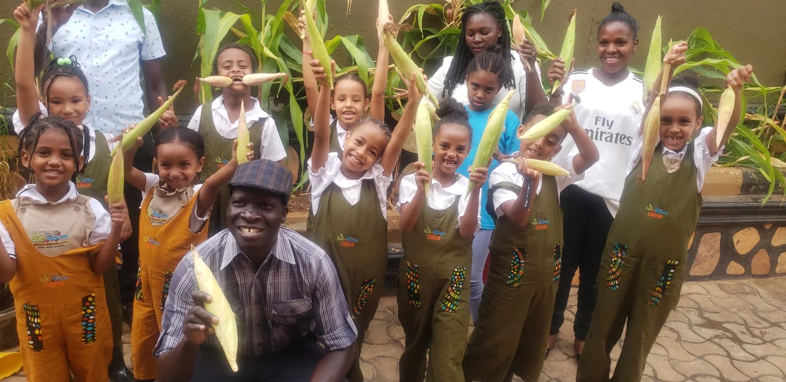 Eco-Bloom children and adults holding freshly harvested maize in the school garden