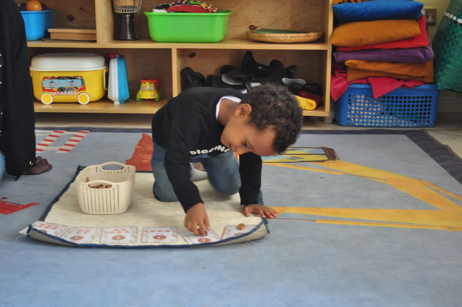 A child working independently with learning materials on a classroom mat at Eco-Bloom