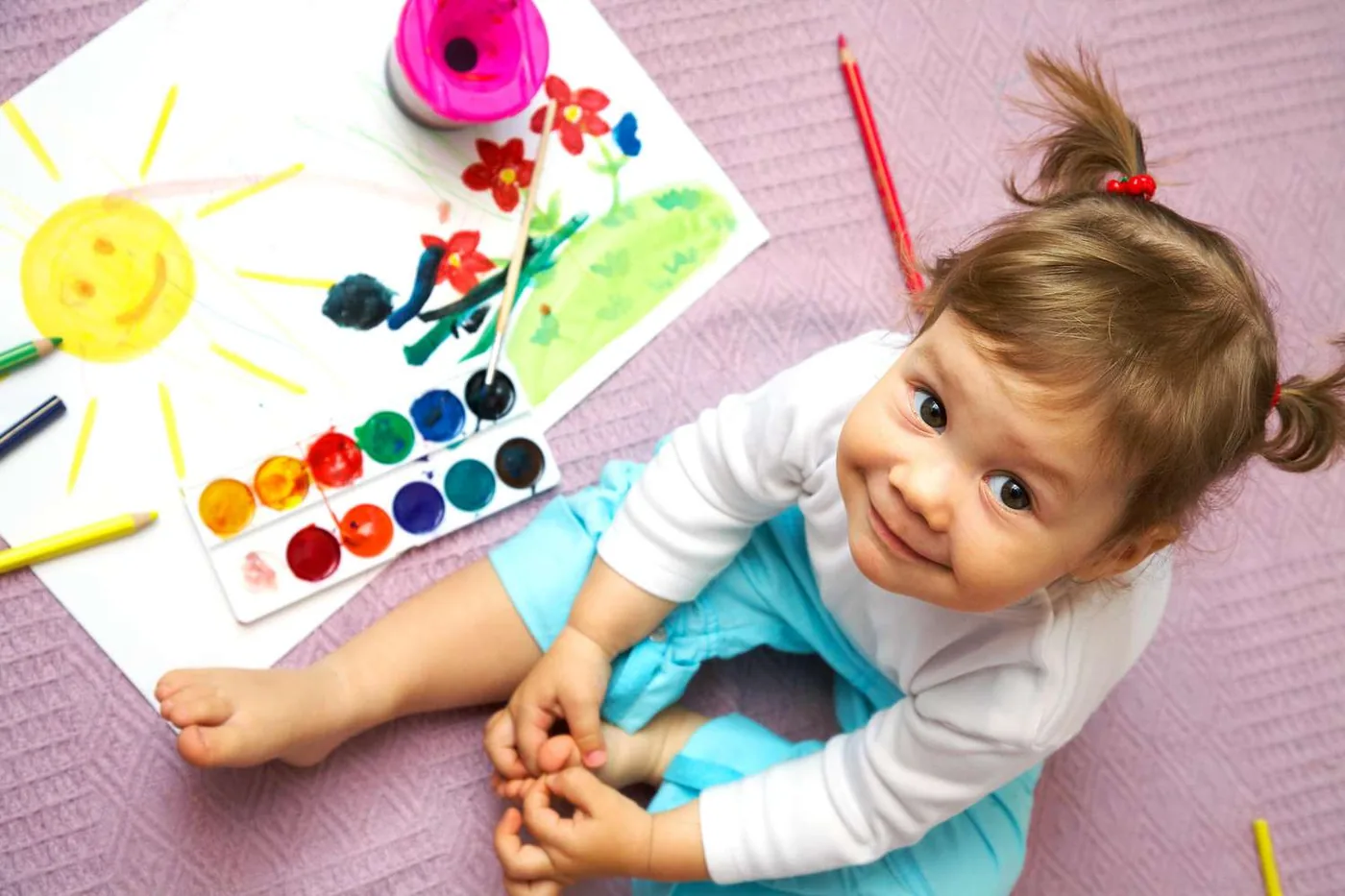 A small child beside a painting she has just finished