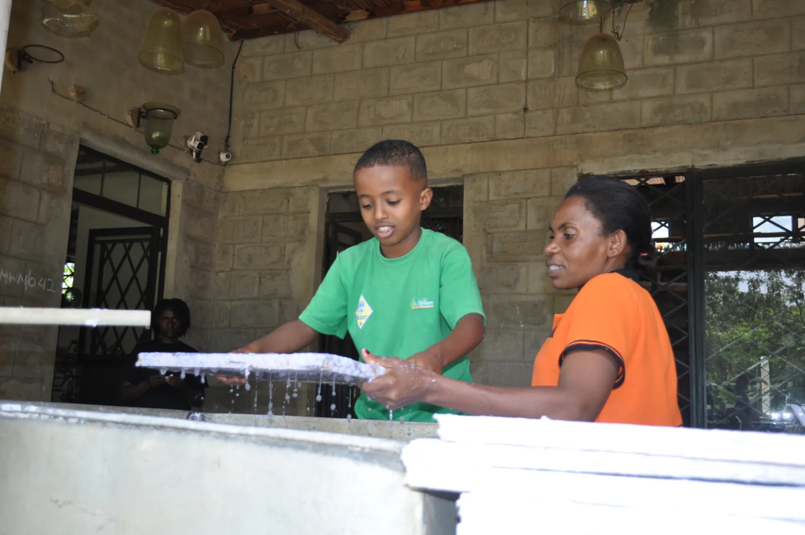 An Eco-Bloom pupil and a guide lifting a paper-making screen during the Paper Craft Africa visit