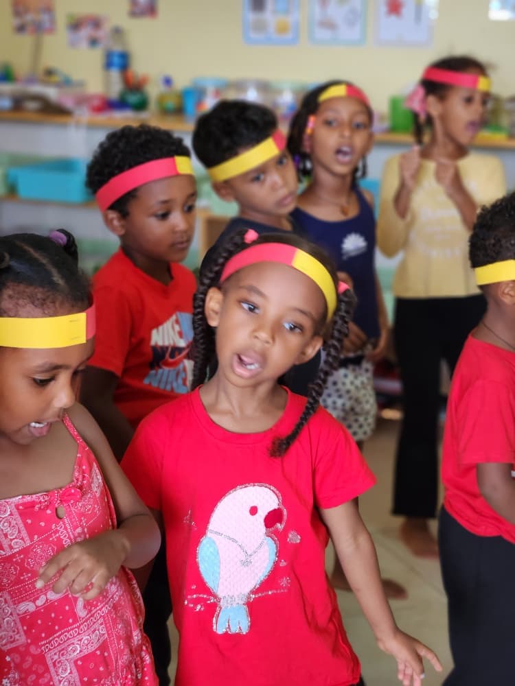 Children singing together in their celebration colours