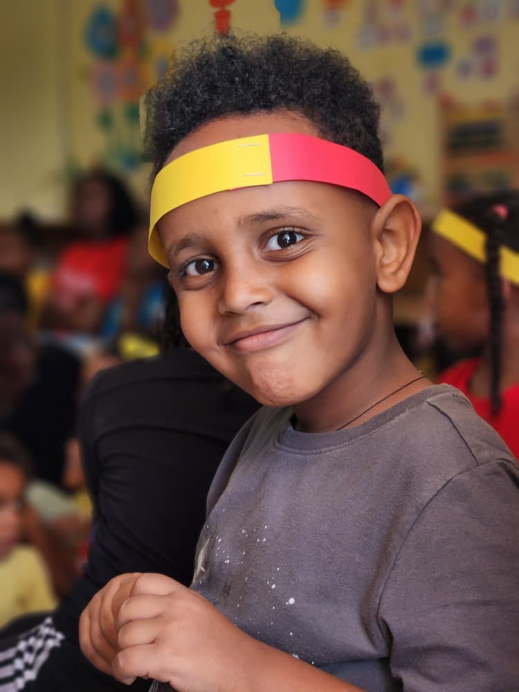 An Eco-Bloom pupil smiling in a red and yellow headband