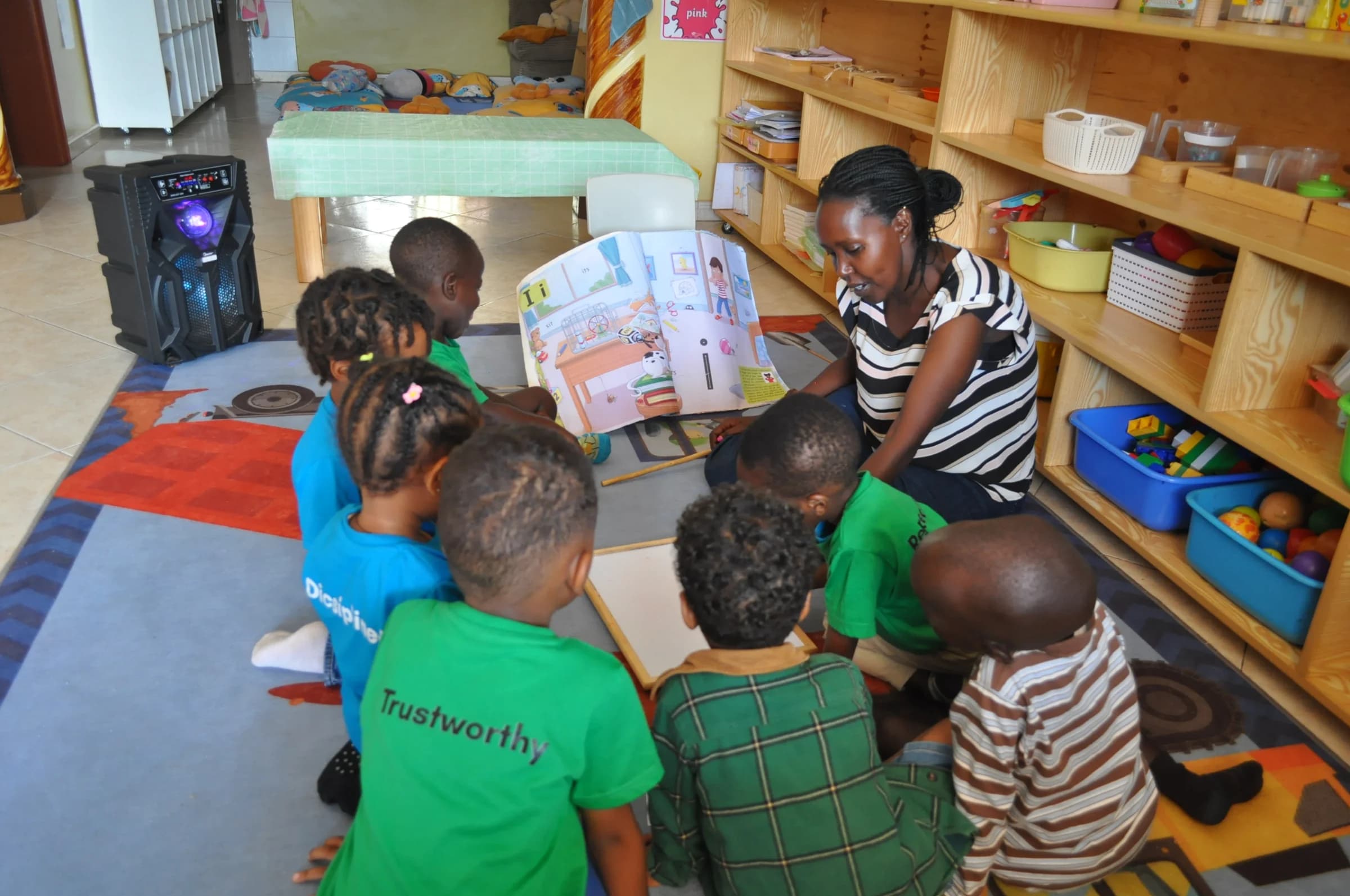 An Eco-Bloom teacher sharing a large picture book with children on the classroom floor