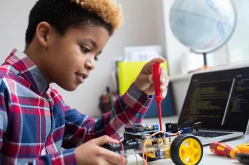 A child assembling a wheeled robot with a screwdriver