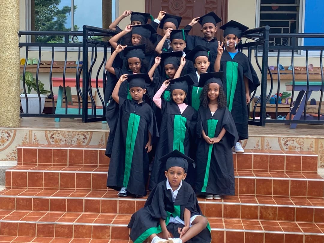 Eco-Bloom children together in black and green graduation gowns and caps