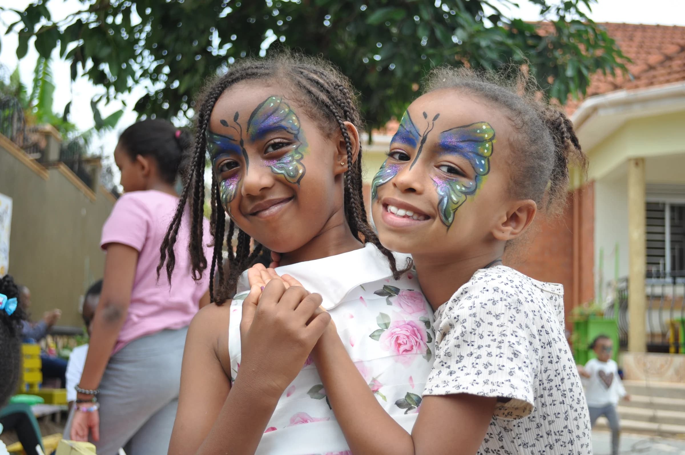 Two Eco-Bloom pupils smiling together with butterfly face paint